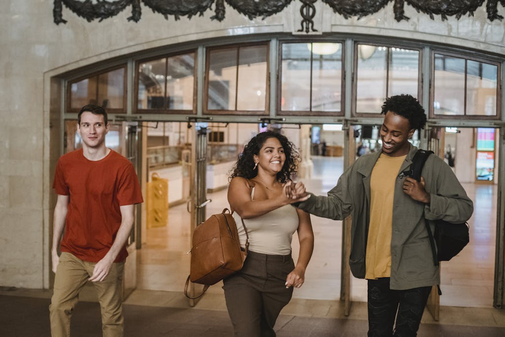 Three diverse friends joyfully walking through an indoor building, bonding and smiling.