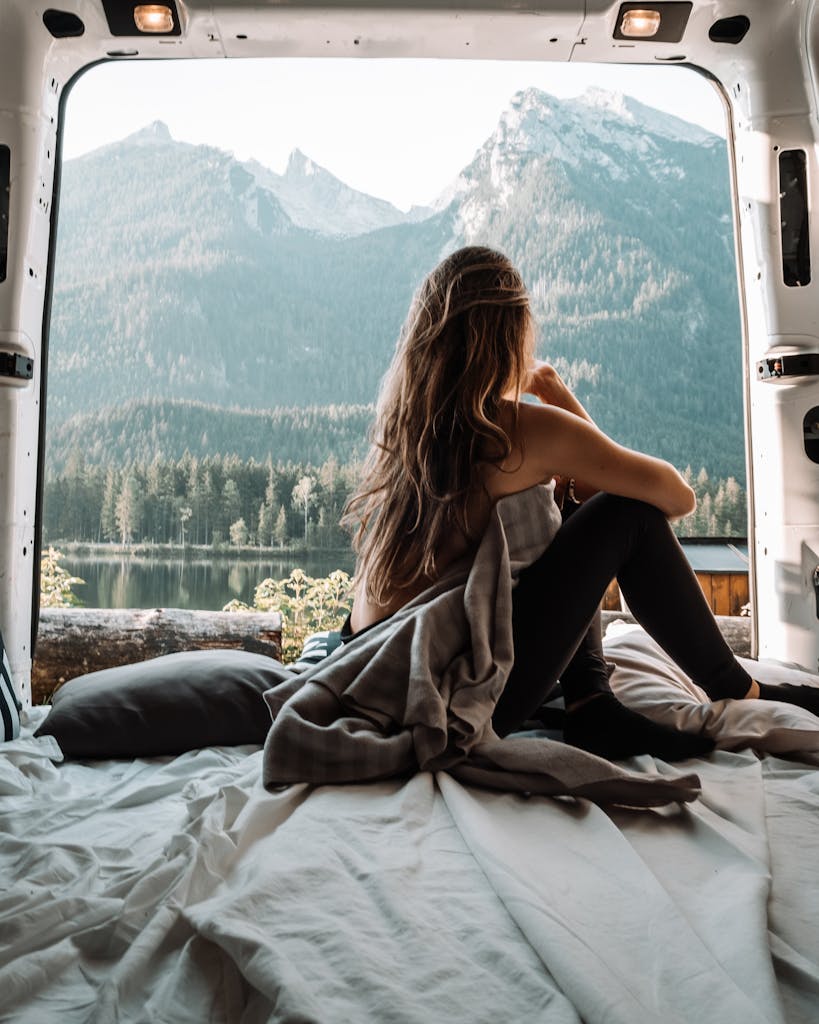 A woman enjoying a peaceful moment inside a campervan with a stunning mountain view, embracing the van life and nature.