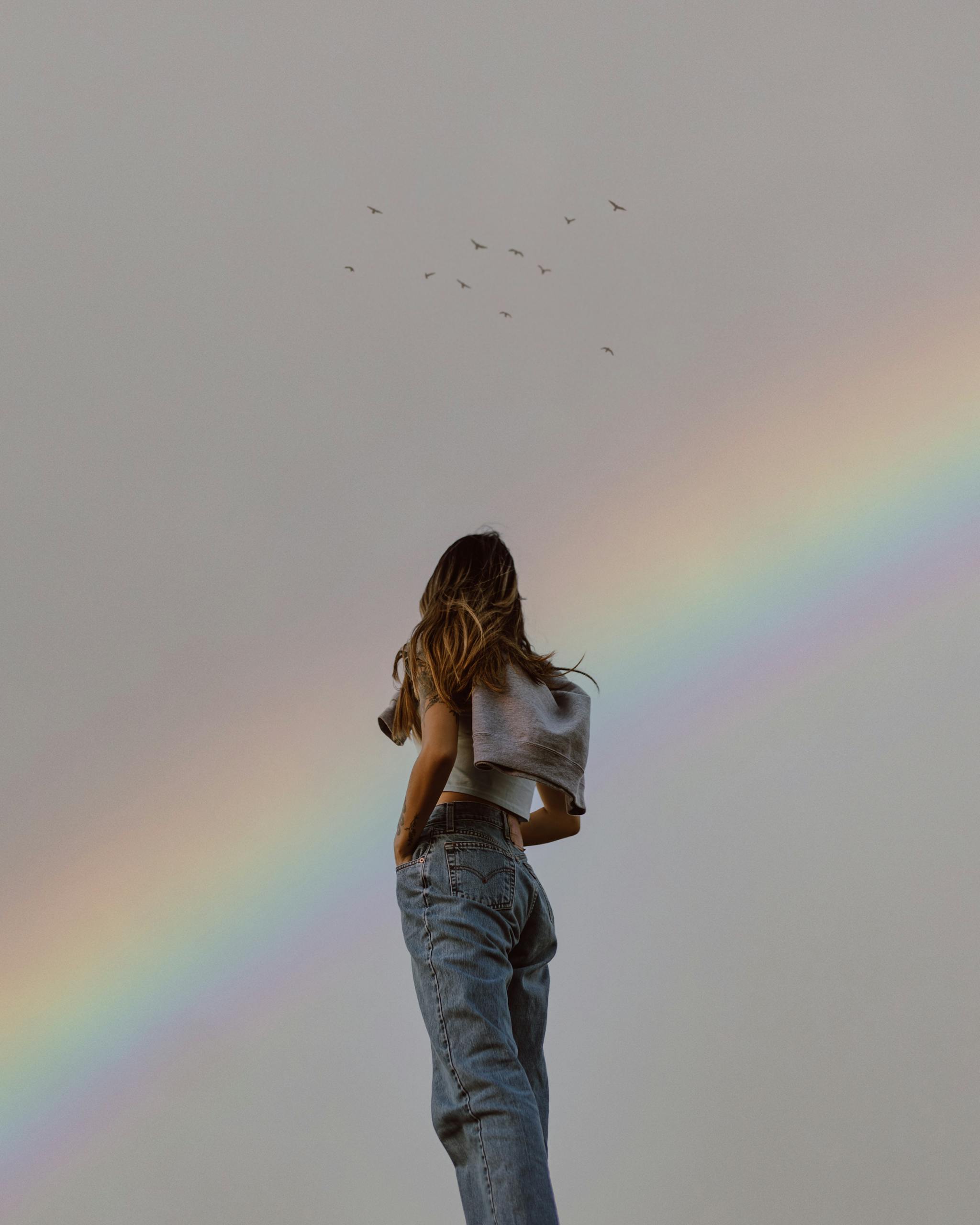 femme regardant un arc en ciel symbolisant la transformation int&eacute;rieure